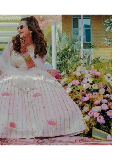 The bride's joyful laugh during her Mehendi ceremony. Her stunning lehenga and the beautiful floral arrangements create a vibrant and happy scene.