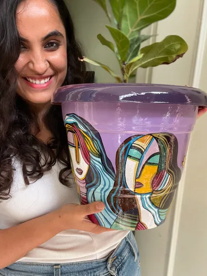 Me holding a large planter painted with my signature abstract face style.