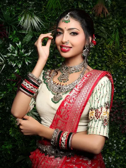 A happy and radiant portrait of a model in a bridal look. Her smile and the way she adjusts her hair create a natural and charming image, highlighting her beautiful jewelry.