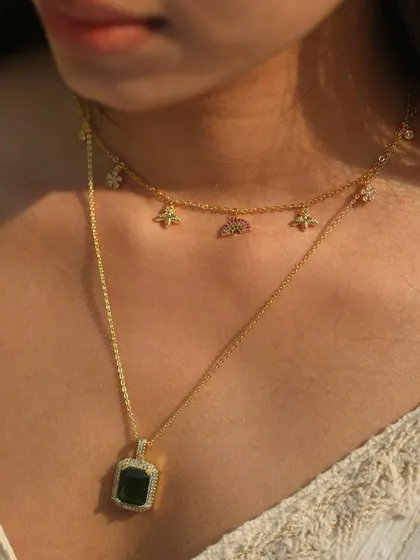 A beautifully layered necklace look. This model wears my enigmatic emerald mix necklace paired with a delicate rainbow charm choker for a touch of elegance.