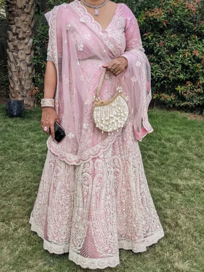 A perfect pink lehenga for a wedding party. The delicate threadwork and matching net dupatta create an elegant and sophisticated look for a wedding guest.