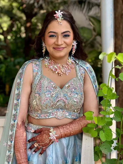 A soft, fresh, and floral Haldi look. The pastel lehenga and floral jewelry are complemented by a soft glam makeup with a pop of blue eyeliner for a modern twist.