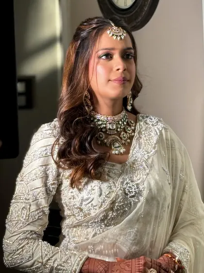 A candid shot of the bride, her natural smile shining through the elegant makeup.