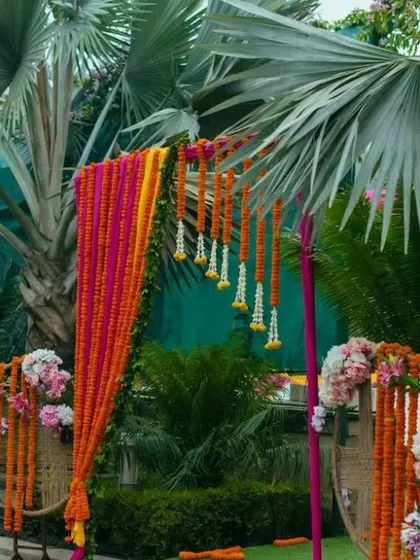 An outdoor decor installation featuring hanging garlands of marigold flowers, perfect for decorating trees or creating entrance pathways.