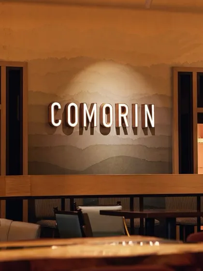 The Comorin sign, glowing softly against a textured wall. It’s a beacon of modern Indian dining, welcoming you to our space.