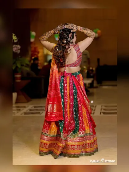 A back shot of the bride, showcasing her colorful Mehendi lehenga and intricate hairstyle.