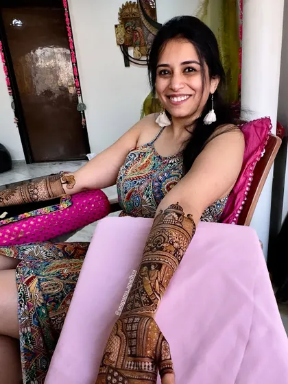 Henna hands and bridal plans. A happy bride-to-be, enjoying the process of getting her intricate mehandi done.