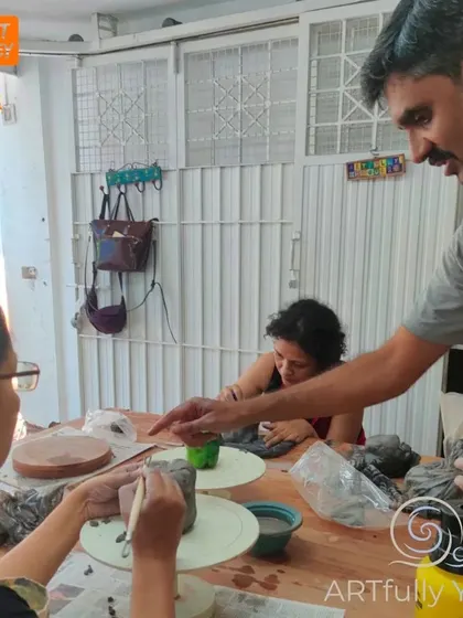 I'm always there to offer guidance and support during my workshops. Here, I'm helping a participant get started with their hand-building project, ensuring they feel comfortable with the clay.