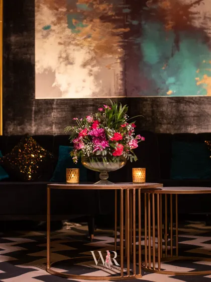 A detail of the lounge seating, showing a vibrant floral centerpiece on a modern gold and marble table. The abstract art in the background adds a contemporary touch to the glamorous setup.