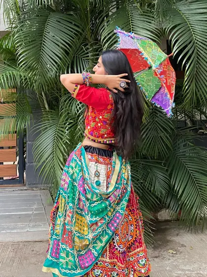 A back view of the multi-colored outfit, showing how the dupatta can be draped and accessorized with a prop umbrella.