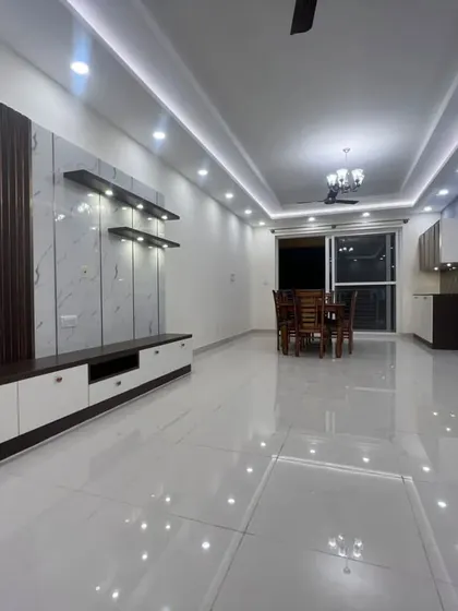 The completed TV unit in a spacious living room, featuring a combination of white marble-finish panels and dark fluted wood. The clean, glossy floor reflects the ceiling lights, enhancing the sense of luxury.