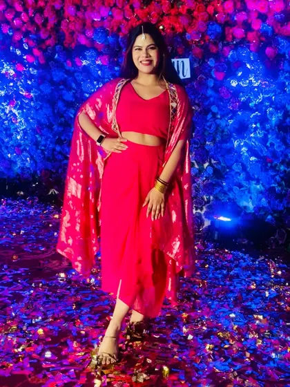 The same pink outfit against a stunning blue and purple floral wall with confetti. The colors just pop.