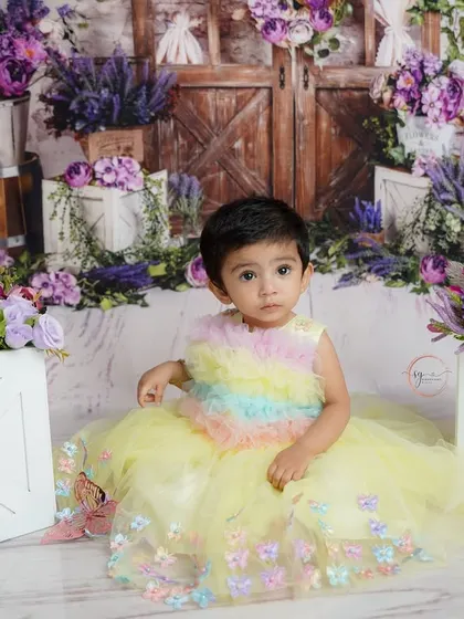 A sweet, seated portrait amidst the floral props, this image showcases the intricate details of the garden theme and the baby's adorable outfit.