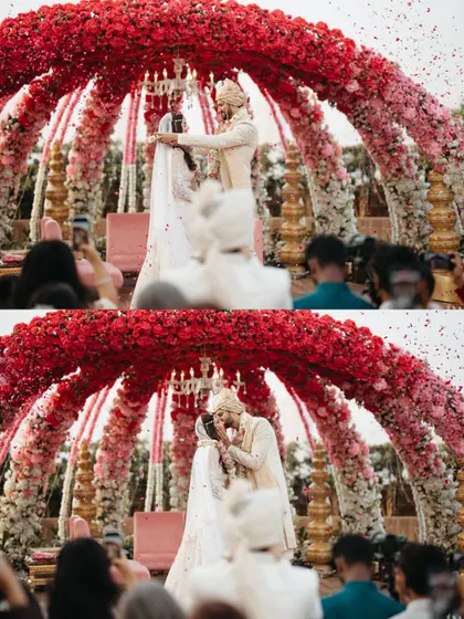 A dramatic shot of the varmala exchange under a massive floral dome, with petals showering down. The scale of the decor makes the moment feel incredibly grand.