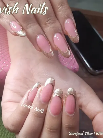 A glamorous French manicure with a sparkling gold glitter tip on long, oval nails, perfect for a festive occasion.
