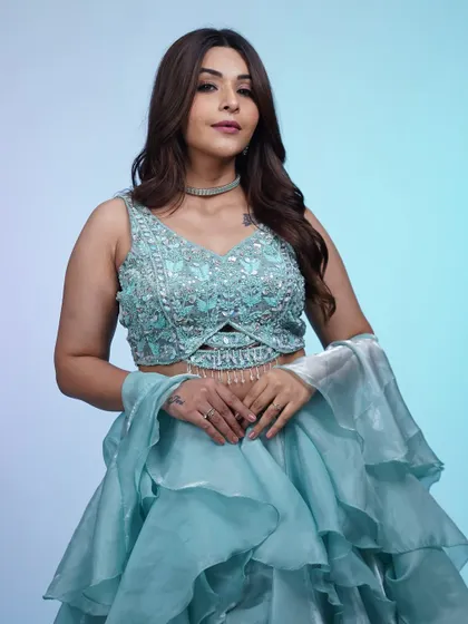 A closer look at the sequined blouse of the ruffled blue lehenga. The intricate beadwork adds a touch of sparkle to this dreamy and ethereal outfit.