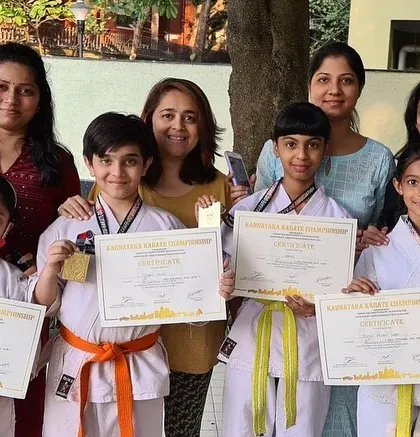 Proud mothers stand with their children, our tournament winners from the Purva Belmont dojo. Success in karate is a community effort.