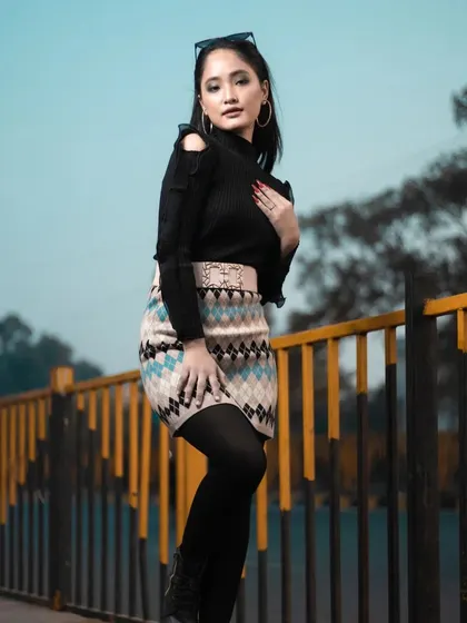 This pose highlights the cold-shoulder detail of the sweater and the overall modern styling of the winter look.