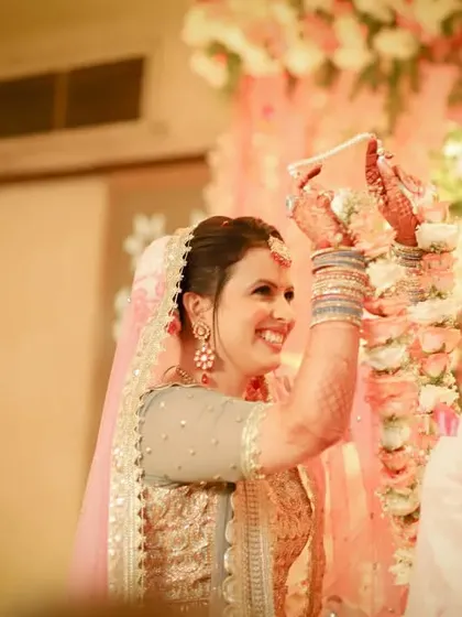 A beautiful, candid shot of the bride smiling as she places the garland on her groom during the Jaimala ceremony. Her happiness is absolutely radiant.