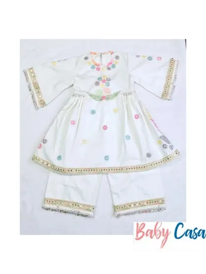 A beautiful white sharara set with multi-colored floral embroidery and mirror work. This is a perfect outfit for a little girl to wear for Diwali or a family puja.