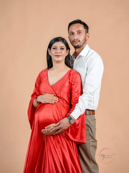 A classic and loving pose for an expecting couple. The partner's hands gently placed on the baby bump symbolize their shared journey into parenthood.