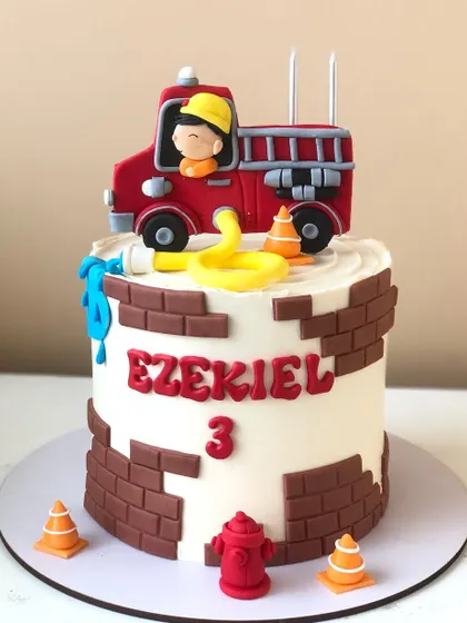 A cute firetruck cake with a brick pattern and a little firefighter ready to save the day.