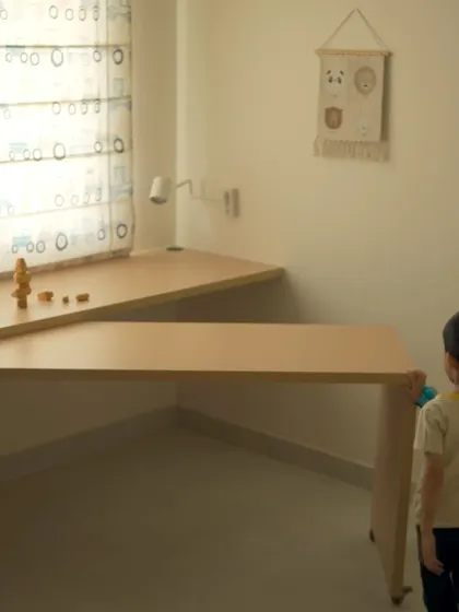This image shows a clever, openable study desk in a child's room. The desk can be folded away to create more play space, demonstrating a focus on multi-functional design.