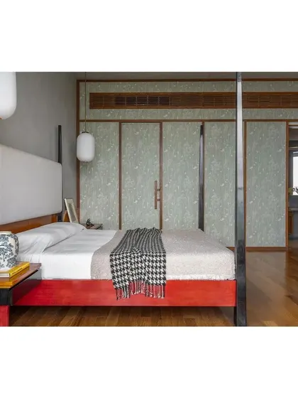 This custom four-poster bed, with its vibrant red lacquered wood base, was inspired by the client's roots and the traditional craft of Channapatna toys. Paired with serene, textured wallpaper panels and warm teak flooring, it becomes the centerpiece of a deeply personal and culturally rich bedroom.