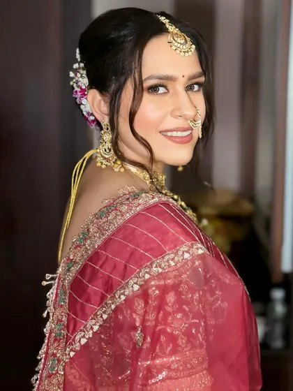 A beautiful bride in a deep red saree, ready for her ceremony. I created a soft, messy updo with fresh flowers and focused on glowing skin and defined eyes for her makeup.