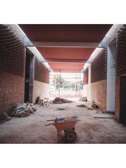 A construction view of the memorial hall, with rubble and a wheelbarrow showing the reality of the building process.