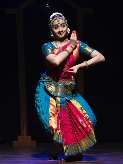 A full-body shot from the Kanasu festival, showing a classic Bharatanatyam pose with clean lines and a joyful expression.
