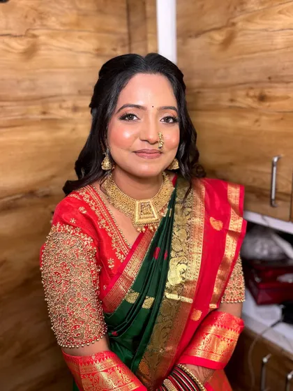 A modern take on the engagement look. The makeup is kept subtle and glowing to match the elegance of her green and red silk saree.