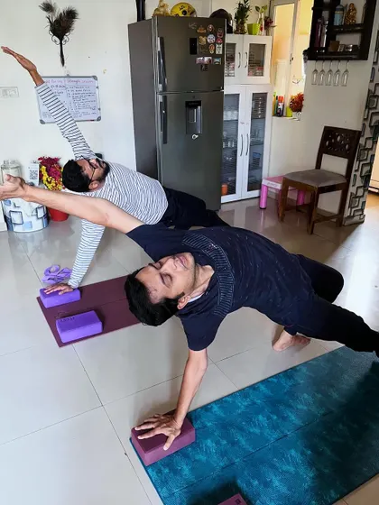 Two clients practice a modified side plank, supporting each other's energy and focus. Group sessions build a sense of community and shared purpose.