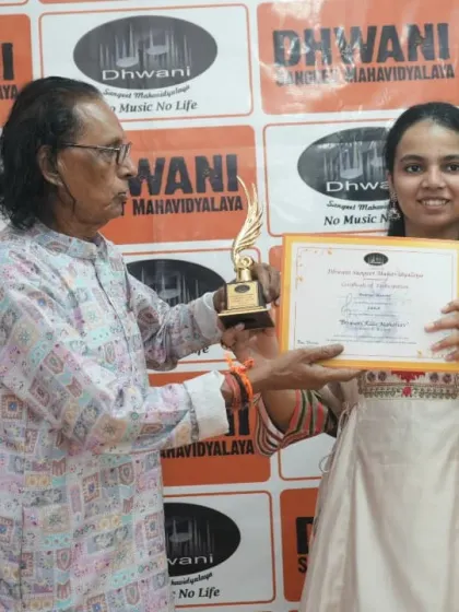 A senior guru presents an award to his student.