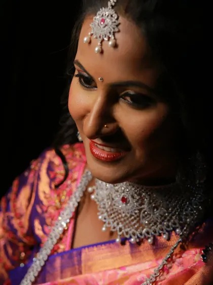A close-up, low-light portrait of a bride, capturing a soft and intimate smile.