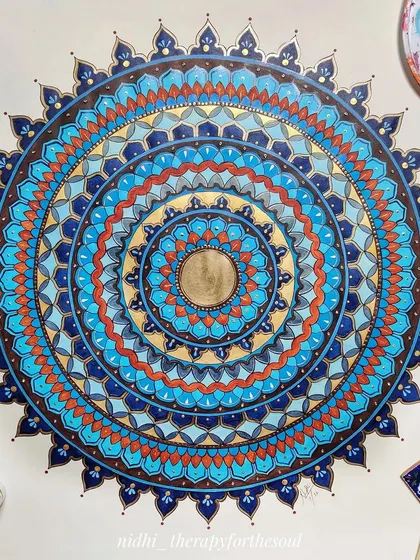 The blue and brown mandala during the painting process, with my palette and brushes nearby. This gives a glimpse into how the layers of color are built up.