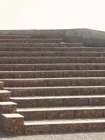 An entrance tunnel is built into the amphitheatre seating, providing access to the stage area. The entire structure is designed to be functional and durable, using materials that will weather naturally over time.