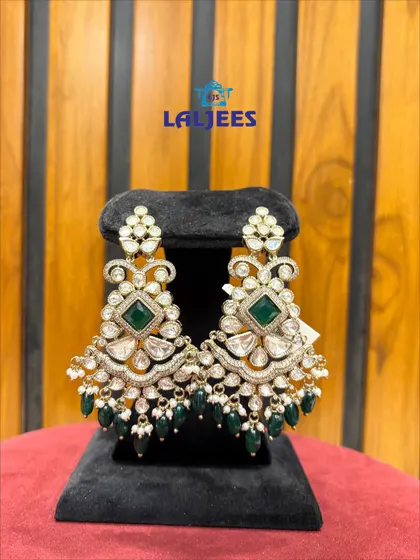 A pair of polki earrings with a square green stone, offering a modern twist to a traditional design.