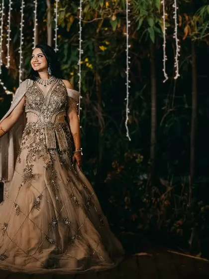 The couple takes a romantic stroll through a garden illuminated by hanging fairy lights. This shot captures a quiet, magical moment away from the celebration, highlighting their elegant evening wear.