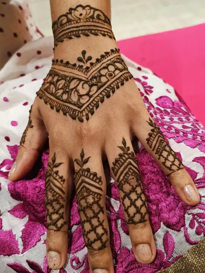 A stylish and modern take on party mehendi. The design uses geometric shapes and chevron patterns on the fingers and wrist, creating a sharp and contemporary look.