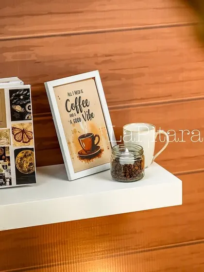 A simple floating shelf against a wood-paneled wall, decorated with a coffee-themed print and a mug. This shows how we carry the theme into every corner of the venue.