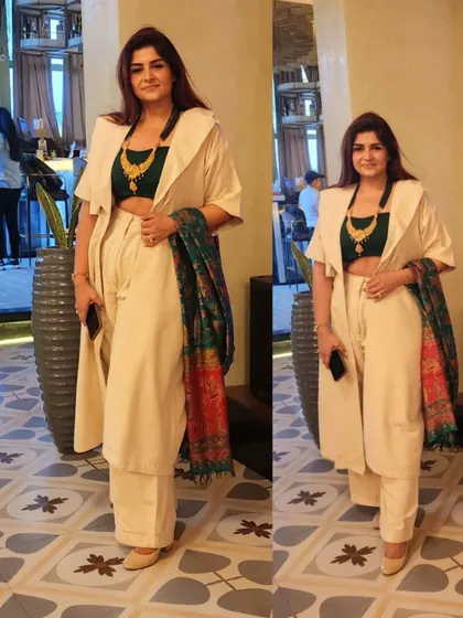 A linen power suit styled as a fusion ensemble. The off-white trench and trousers are paired with a contrasting green crop top and a traditional Banarasi silk dupatta for a pop of color.