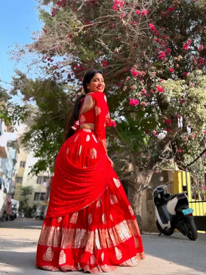 This vibrant red half saree is perfect for making a statement. The gold block prints on the skirt and the matching full-sleeve blouse create a look that is both traditional and bold.