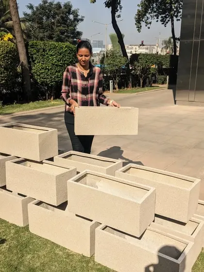 A team member holds up one of the rectangular FRP planters to show how light and manageable it is. This feature is a significant advantage during large-scale installations like this one.
