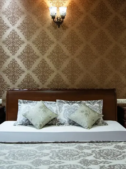 A close-up of the bed and side tables, highlighting the detailed woodwork and the classic lamp that adds to the room's warm ambiance.