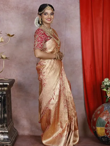 A classic muhurtham look featuring a peach and red Kanchi silk saree with a fully embroidered red blouse.