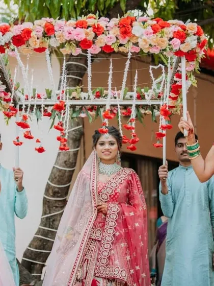 The bride's entry is one of the most special moments of any wedding. Here, we captured her walking in under a beautiful 'phoolon ki chadar' held by her family. The soft lighting and her happy expression make this a perfect, heartfelt shot.