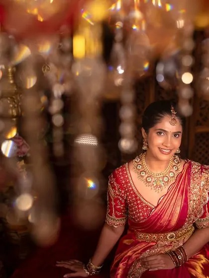 A portrait of the bride smiling, with the warm, blurry lights of chandeliers creating a magical bokeh effect. This shot captures her happiness in a beautiful, artistic way.