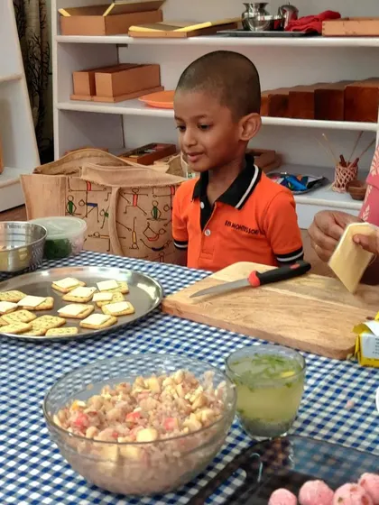 A child watches intently as a teacher prepares ingredients for a cooking activity. Observation is a key part of learning in a Montessori environment before the child attempts the task themselves.