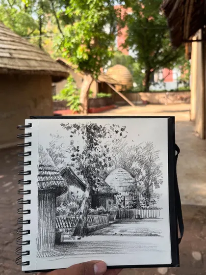 The finished live pencil landscape sketch from my visit to the Craft Museum in Delhi, held up against the actual scene.